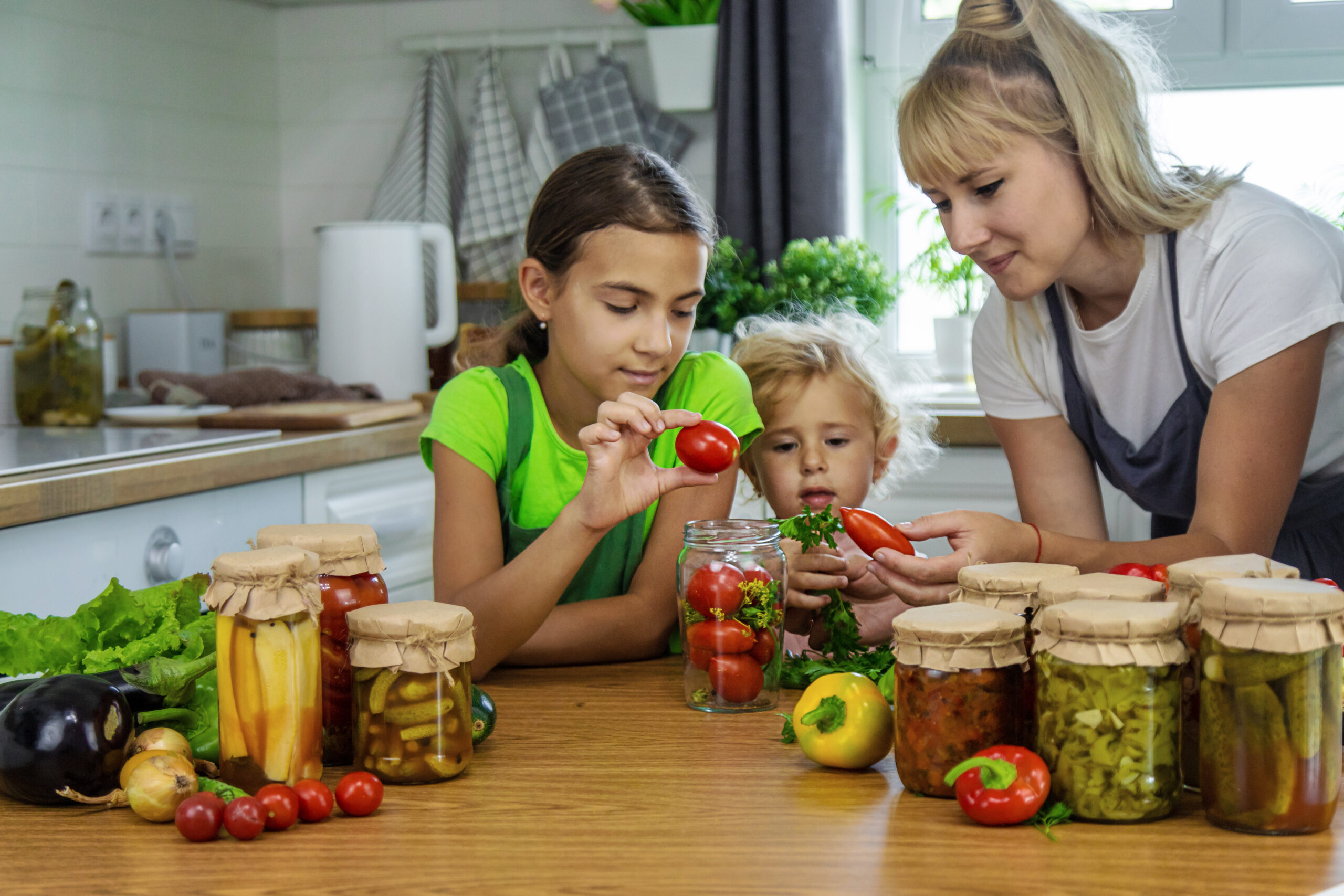 Family canning vegetables in jars in the kitchen.